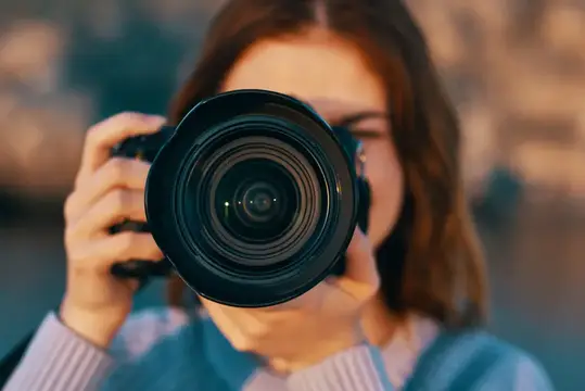 Девушка фотографирует через объектив камеры на закате