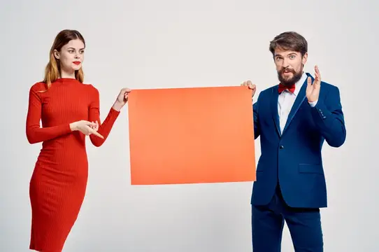Весёлые мужчина и женщина проводят презентацию, посвящённую скидкам и рекламному плакату