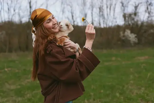 Женщина на улице с собакой, улыбка и счастье, нежный момент с цветком в ярком парке