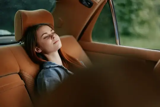 Красивая молодая женщина с рыжими волосами отдыхает в автомобиле, воплощая безмятежность