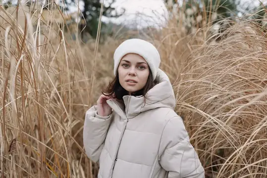 Портрет женщины в теплом пальто среди сухой травы