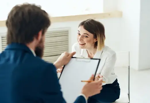 Улыбающаяся женщина на собеседовании с мужчиной с планшетом