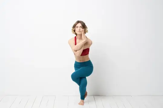 Спортивная женщина в светлой комнате занимается йогой в полный рост