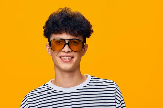 Улыбающийся парень в оранжевых очках на жёлтом фоне