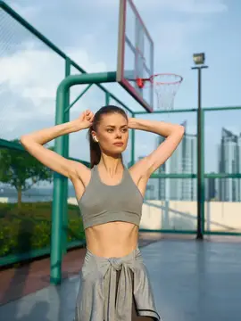 Спортивная девушка отдыхает на баскетбольной площадке летом