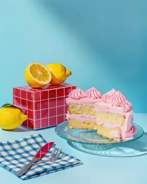 Вкусный кусок торта с розовой глазурью и ломтиками лимона на синей скатерти для любителей сладкого
