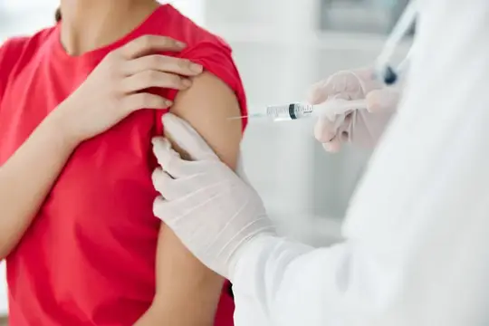 Врач крупным планом делает инъекцию вакцины в плечо женщины-пациента