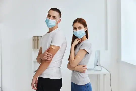 Мужчина и женщина в масках после вакцинации в светлом кабинете