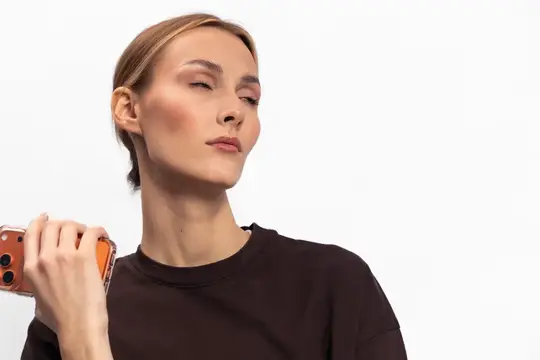 Молодая женщина с закрытыми глазами держит смартфон на белом фоне