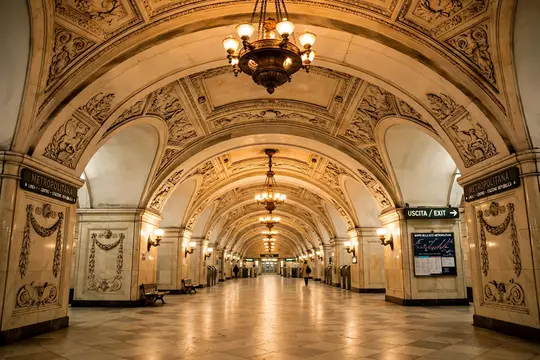 Пустынный зал старинной станции метро с лепными арками и люстрами