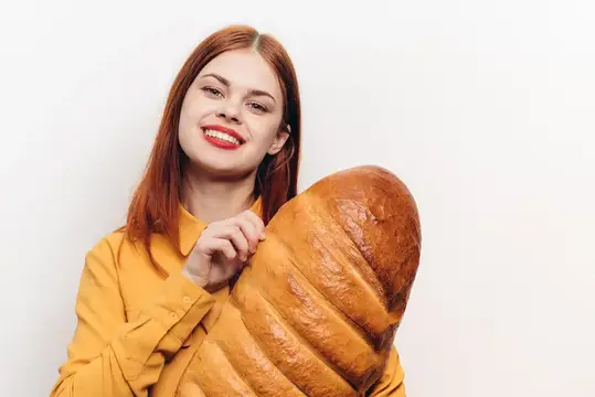 Симпатичная женщина с батоном в руках на светлом фоне, красные губы, макияж, модель