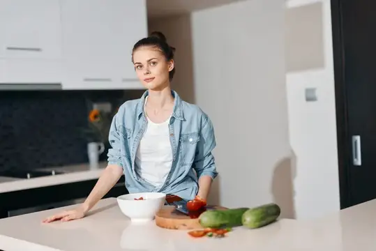 Здоровый образ жизни на кухне: молодая женщина европейской внешности наслаждается свежим вегетарианским салатом дома