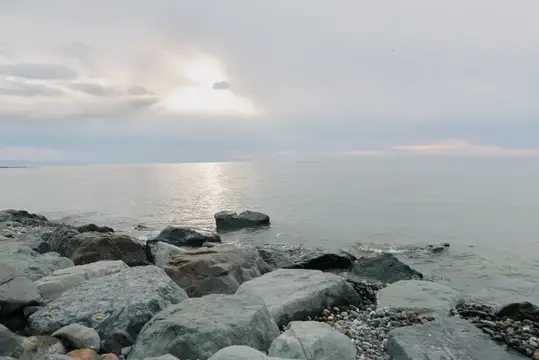 Спокойное море с каменистым берегом под пасмурным небом