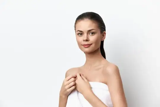 Молодая женщина с полотенцем на плечах на белом фоне
