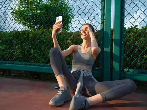 Спортивная девушка делает селфи на корте у зеленой сетки
