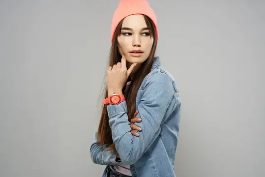 Задумчивая девушка в розовой шапке и джинсовой куртке