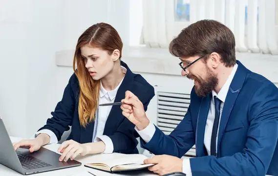 Мужчина и женщина в офисах обсуждают работу за ноутбуком
