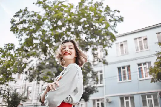 Весёлая женщина весело проводит время на улице возле дерева