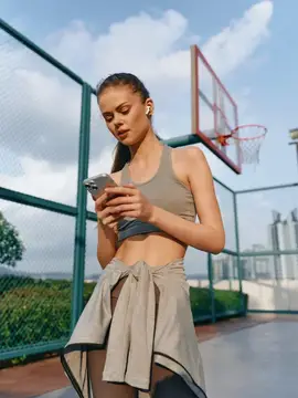 Спортивная девушка со смартфоном на баскетбольной площадке