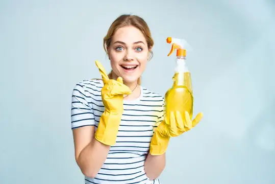 Улыбающаяся девушка в жёлтых перчатках с чистящим средством