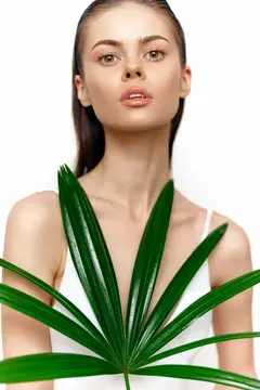 Потрясающая модель демонстрирует естественную красоту, держа ярко-зеленый лист, символизирующий здоровье и экологичность