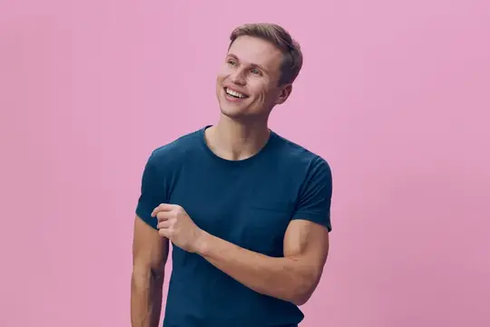 Улыбающийся парень в синей футболке на розовом фоне