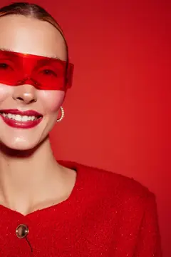 Улыбающаяся девушка в красных очках на красном фоне