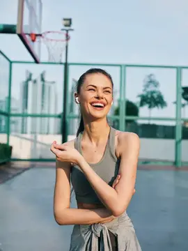 Улыбающаяся девушка в спортивной форме на баскетбольной площадке