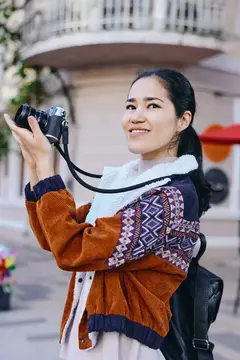 Камера, фотография, улица, женщина в свитере с рюкзаком и объективом наслаждается уличной фотографией в солнечный день среди городской суеты, демонстрируя преданность своему делу и подлинную…