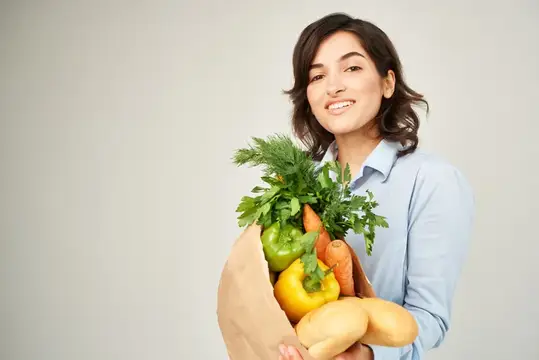 Брюнетка с пакетом полезных продуктов совершает покупки в супермаркете