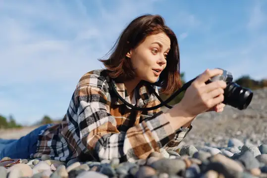 Женщина-фотограф на гальке на пляже