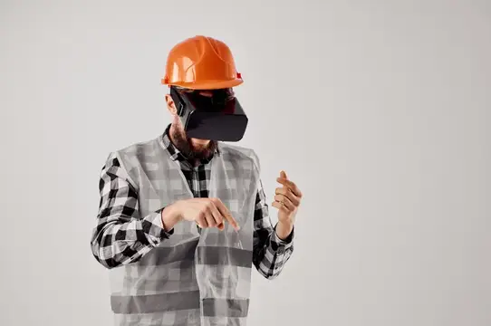 Строитель в оранжевой каске и VR-очках показывает жестами