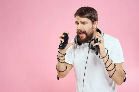 Мужчина с джойстиками в руках, в наушниках, веселье, эмоции, игра, розовый фон