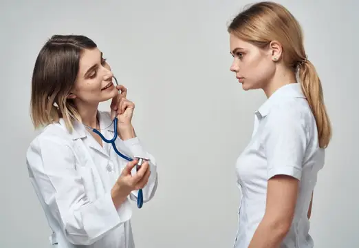 Женщина-врач со стетоскопом слушает пациентку в белом халате