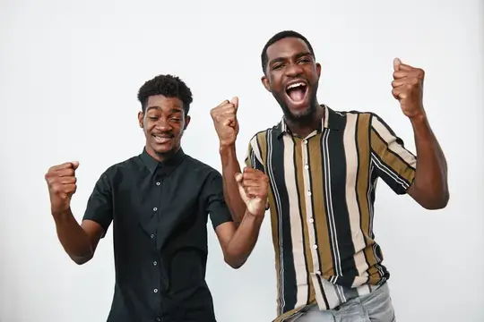 Двое темнокожих мужчин радостно празднуют успех с поднятыми кулаками