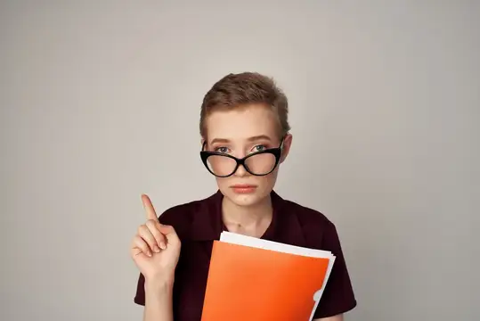 Молодая женщина с короткой стрижкой в очках поднимает указательный палец с папкой