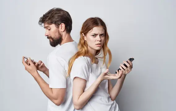 Мужчина и женщина стоят спиной к спине со смартфонами и ссорятся
