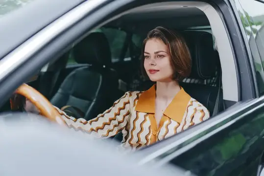 Молодая женщина с короткой стрижкой за рулём автомобиля