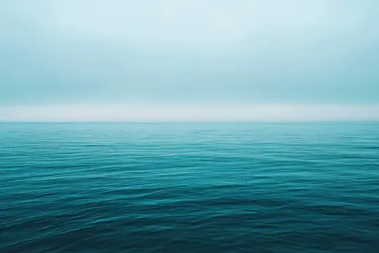 Мирная прибрежная сцена со спокойными бирюзовыми водами под легкой дымкой, вызывающая чувство умиротворения