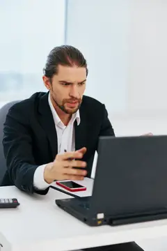 Сосредоточенный мужчина в костюме работает за ноутбуком в офисе