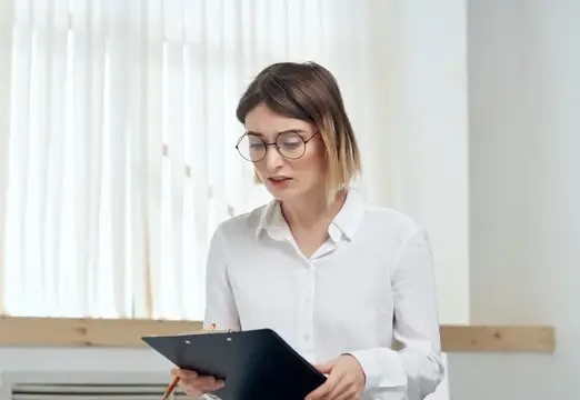 Деловая женщина в белой рубашке держит в руках папку для офисных бумаг