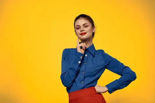 Задумчивая девушка в синей рубашке на жёлтом фоне