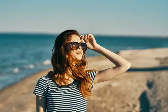 Портрет женщины в футболке и солнцезащитных очках на пляже, свежий воздух, отпуск