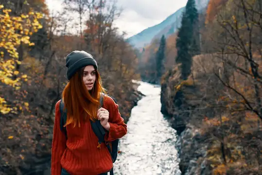 Женщина с поднятыми вверх руками на природе в горах, осенний лес