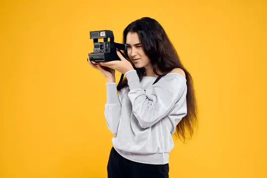 Девушка с ретро-фотоаппаратом на жёлтом фоне