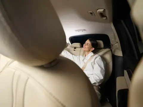 Улыбающаяся темноволосая женщина на заднем сиденье автомобиля