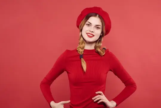 Улыбчивая девушка с косами в красном берете на красном фоне