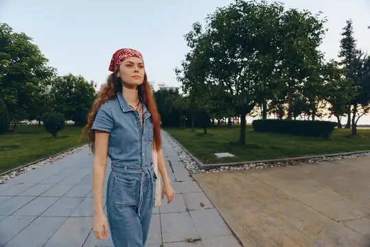 Женщина в стиле life-style, одетая в современный бохо-вестерн джинсовый уличный стиль, прогуливается по парку, излучая расслабленную уверенность и естественную красоту, снятая с эффектами теплого…