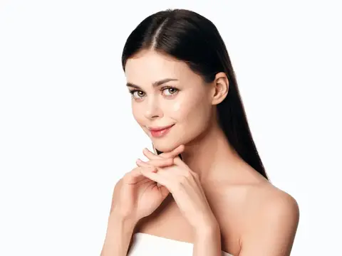 Молодая брюнетка с ухоженной кожей мягко улыбается на белом фоне