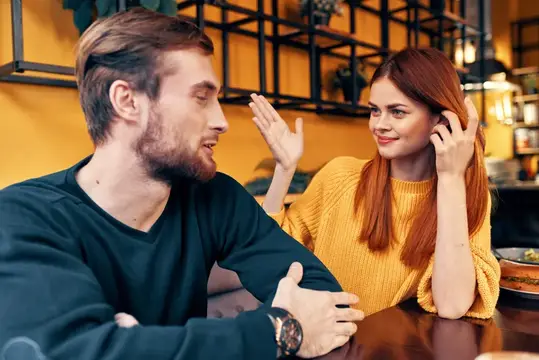 Мужчина и женщина сидят в кафе за столом и жестикулируют руками, друзья, эмоции, веселье, интерьер